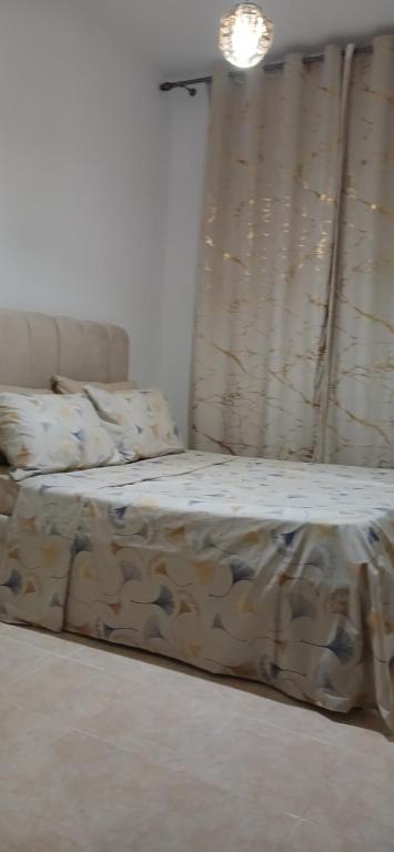 a bed sitting in a room with a curtain at Relax nouvelle ville ibn batouta2 in Oulad Akkou