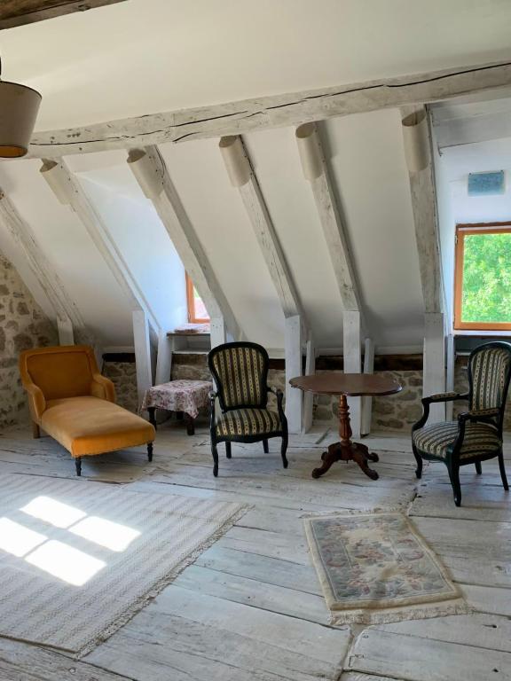 Cette chambre mansardée dispose de chaises et d'une table. dans l'établissement Maison D'Augusta, à Mayrinhac-Lentour