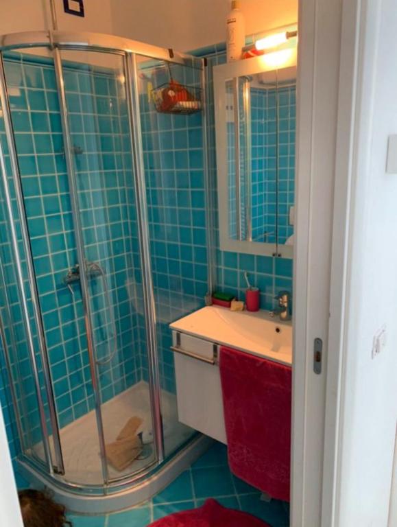 La salle de bains est pourvue de carrelage bleu, d'une douche et d'un lavabo. dans l'établissement Studio in cannes Croisette, à Cannes