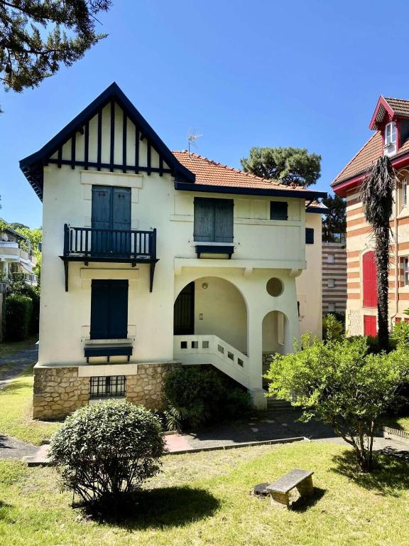 une maison blanche avec des fenêtres bleues et une cour dans l'établissement Résidence 385-arcachon - Appartement cosy pour famille, avec parking et balcons privés MAE-8884, à Arcachon
