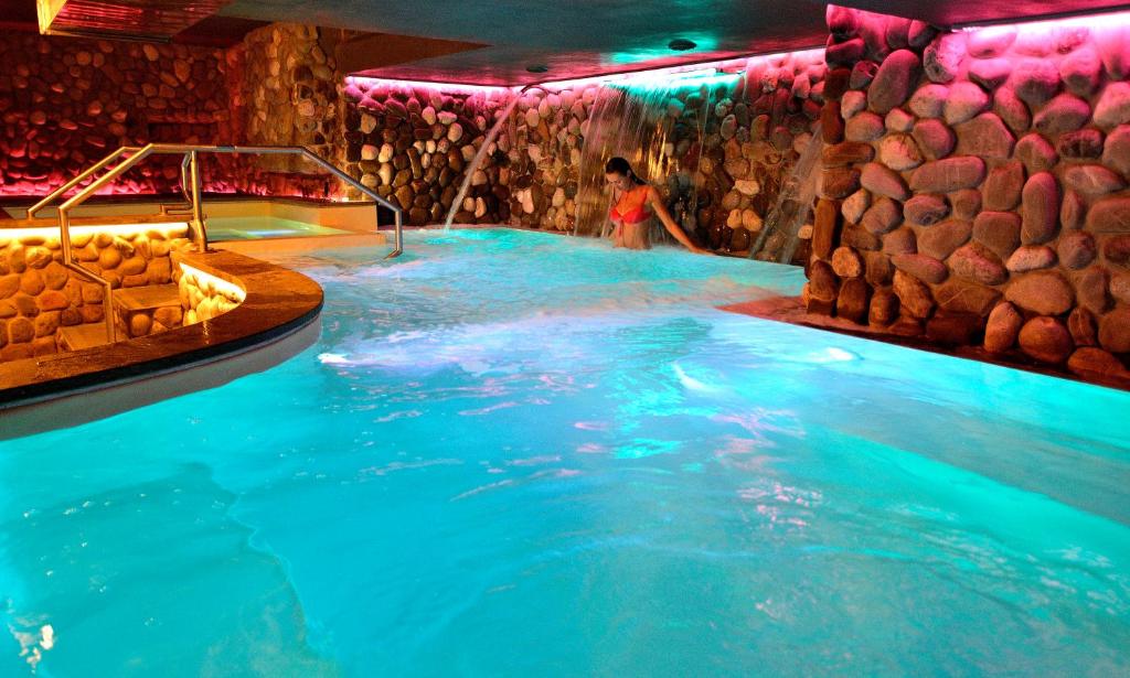 Una donna è in una vasca idromassaggio in una piscina di Hotel Del Buono Wellness & Medical Spa a Chianciano Terme
