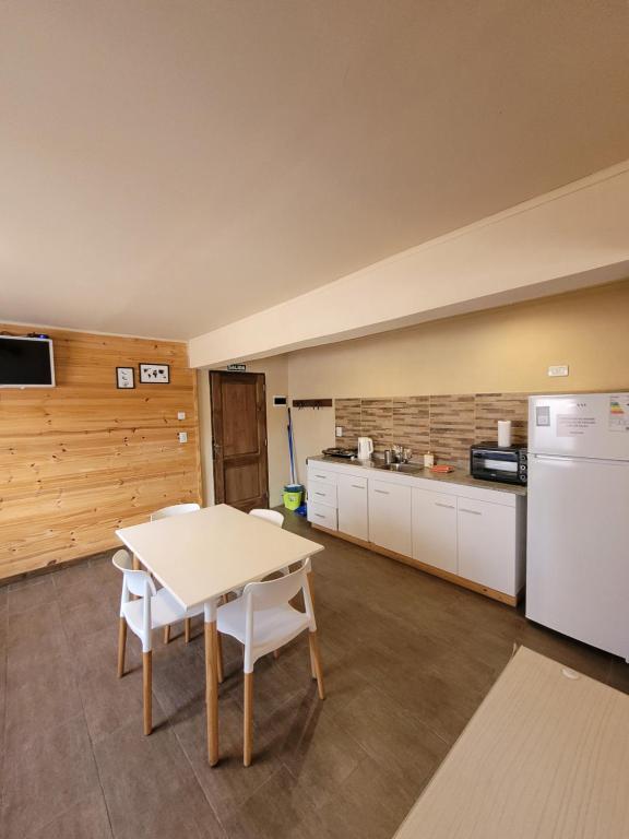 a kitchen with a table and a white refrigerator at Baguales Alojamientos Patagonicos in Villa La Angostura