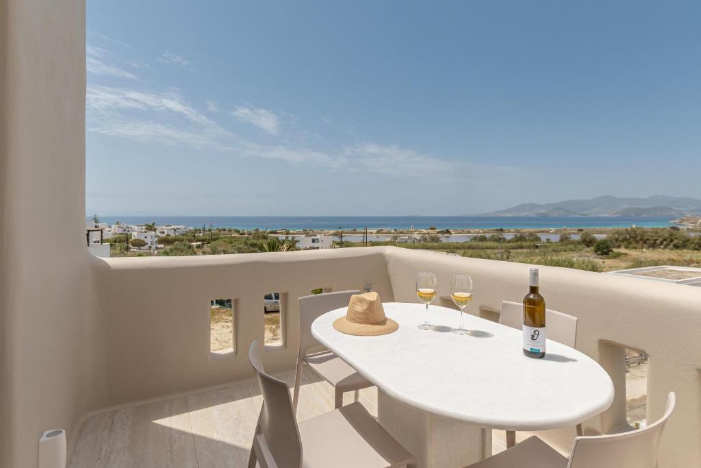 a white table with two glasses of wine on a balcony at Villa Adriana Hotel in Agios Prokopios