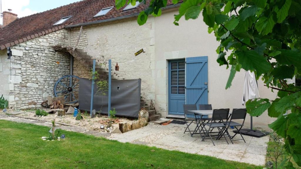 une maison avec une porte bleue, une table et des chaises dans l'établissement Gîte Elendil - Esprit Champêtre, à Chambon