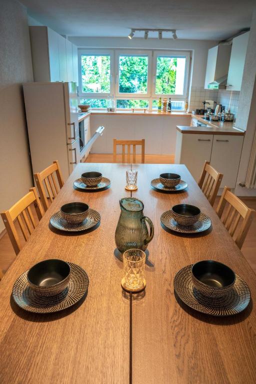 a wooden table with place settings on it in a kitchen at Grill & Chill-Kressbronn Deluxe in Kressbronn am Bodensee