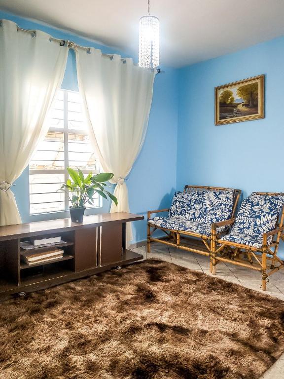 a living room with a table and a couch and a window at Sobrado Azul com Piscina in Boituva