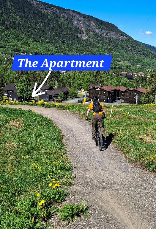 a man riding a bike down a dirt road at Alpinlandsbyen - Ski in - Ski out -Nr 34 in Hafjell