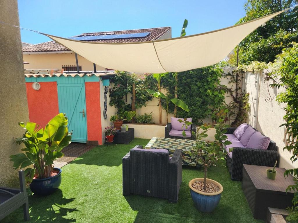 une arrière-cour avec une terrasse entourée d'herbe verte dans l'établissement Appartement ensoleillé Perols, à Pérols