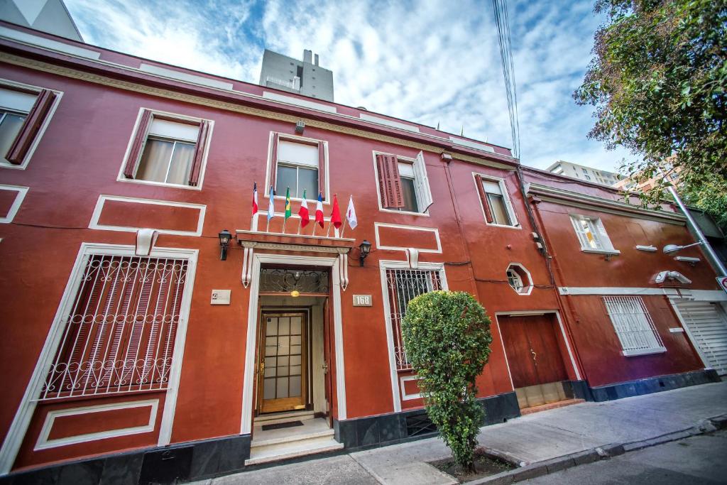 a red building on a street with a tree in front at Hotel Sahara Inn in Santiago