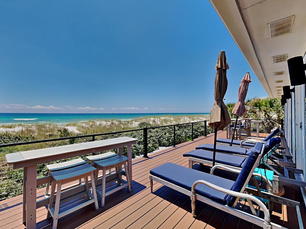 a deck with chairs and an umbrella and the beach at Blue Heron in Pensacola Beach
