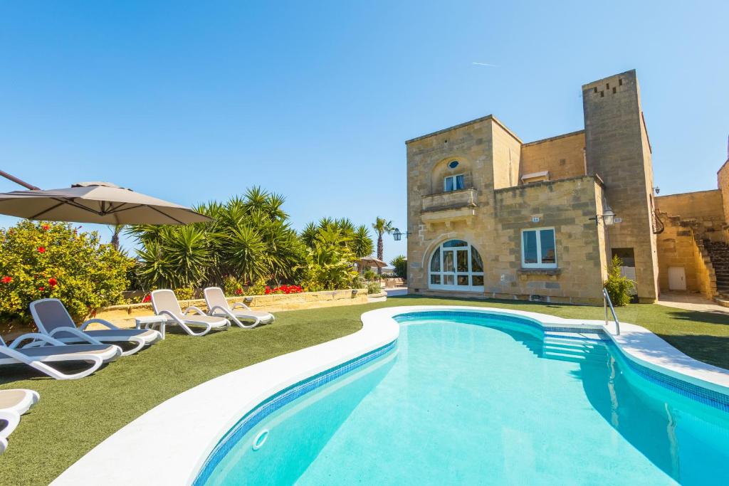 a villa with a swimming pool in front of a building at Nirvana Gozitan Villa & Pool - Happy Rentals in Qala