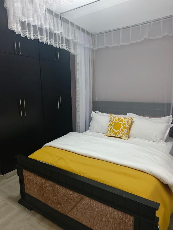 a bedroom with a large bed with a yellow pillow at Nsuube Apartment in Mukono