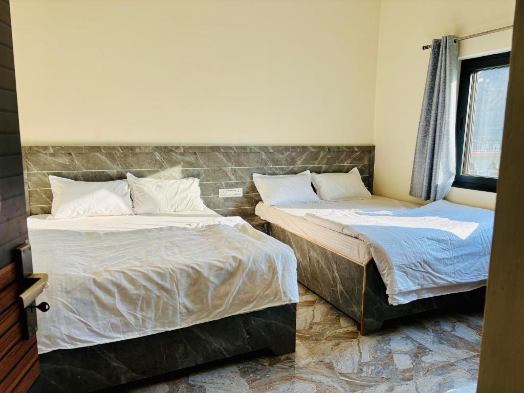 two beds sitting next to each other in a room at Juyal palace in Jāmb