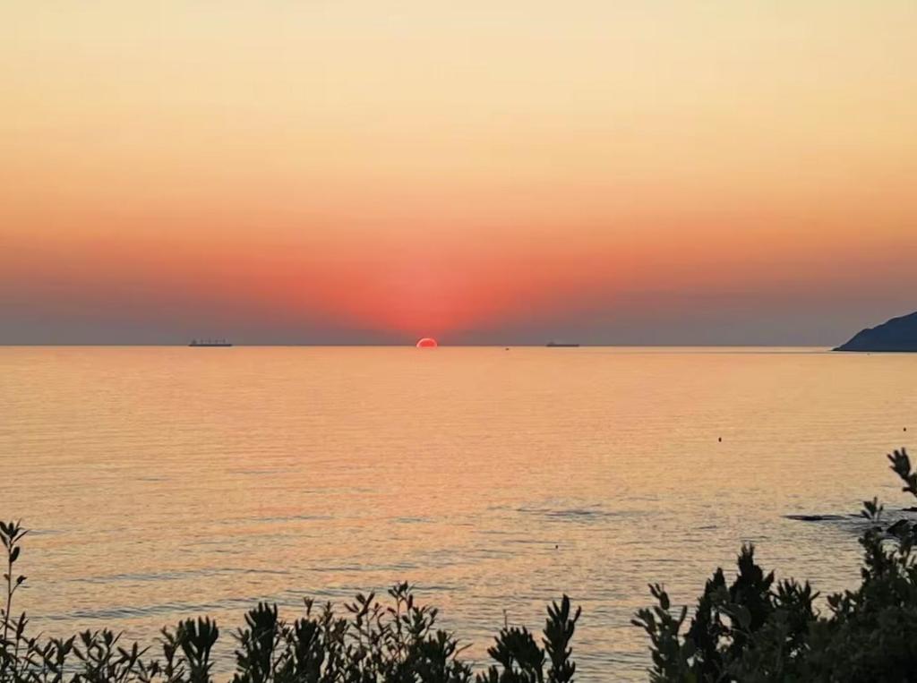 una puesta de sol sobre una gran masa de agua en 2 Tuscan seafront apartments with private access to sea, en Castiglioncello