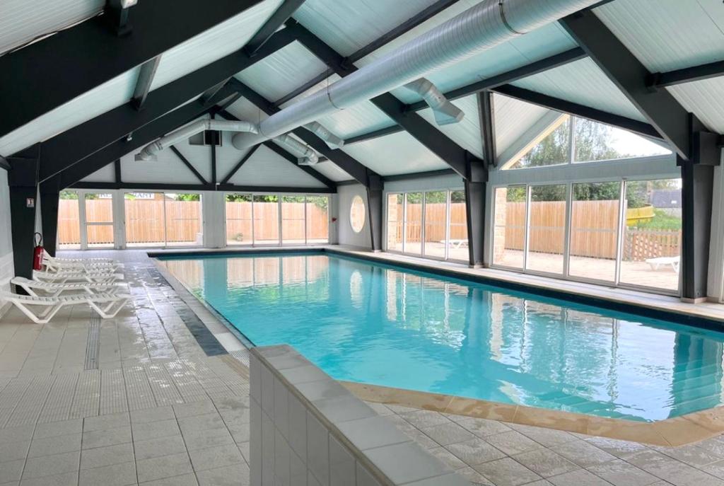 a large swimming pool with blue water in a building at Chalet au calme pour 6 personnes proche Golfe du Morbihan Animaux acceptés in Sulniac