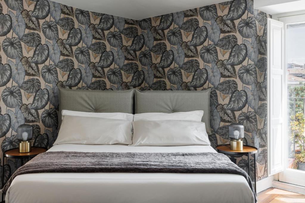 a bedroom with a bed and a wall with birds wallpaper at Casa Dona - Essenza in Catania