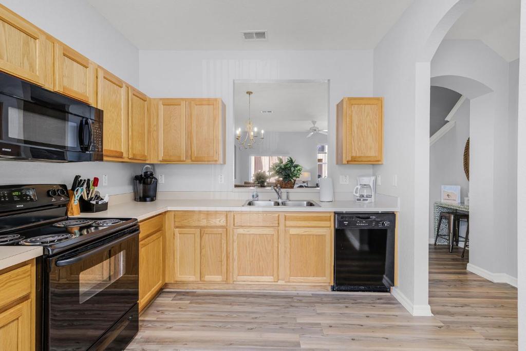 a kitchen with wooden cabinets and a black dishwasher at Camaro in Orlando