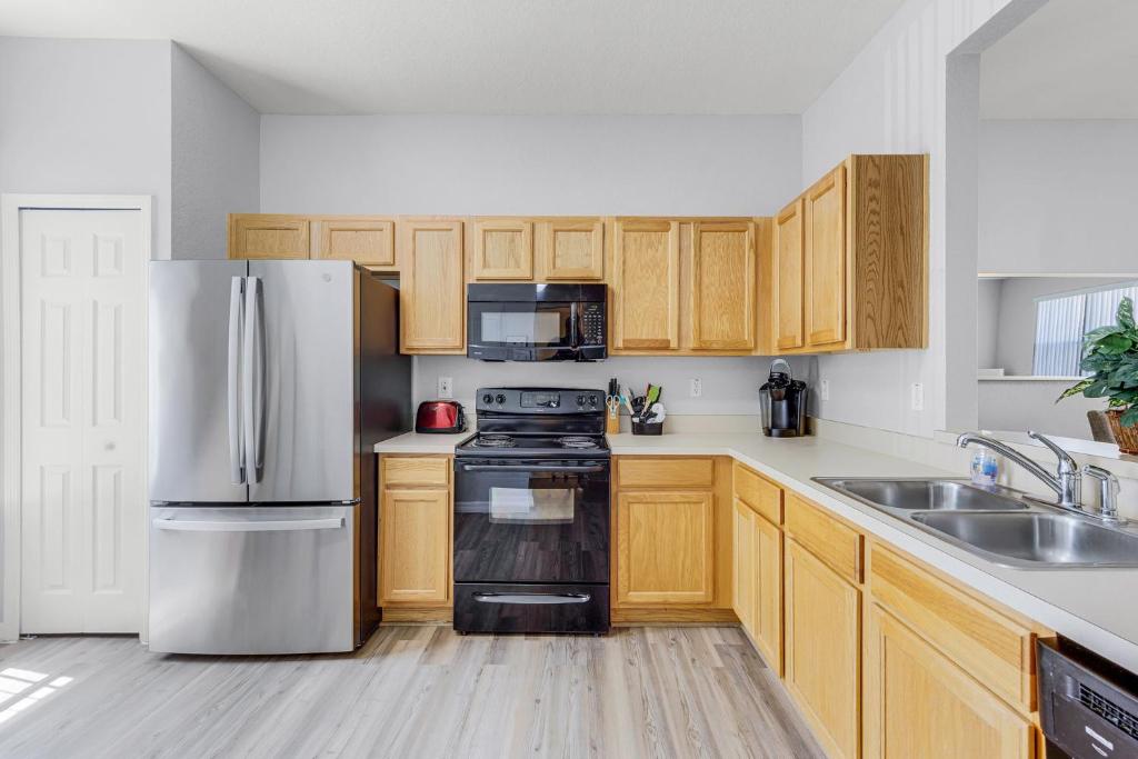 a kitchen with wooden cabinets and a stainless steel refrigerator at Camaro in Orlando