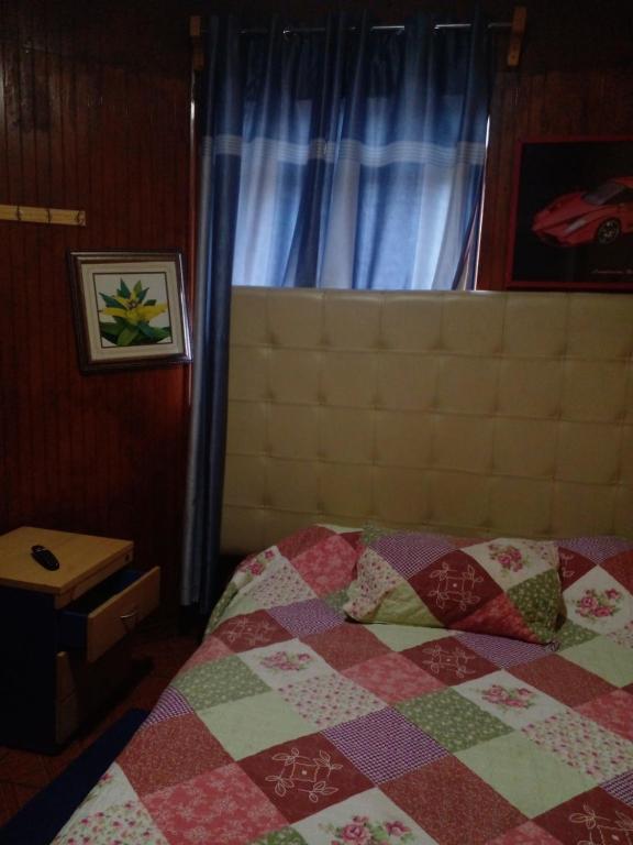 una camera da letto con un letto con una trapunta sopra di Hostal Palmera a Rancagua