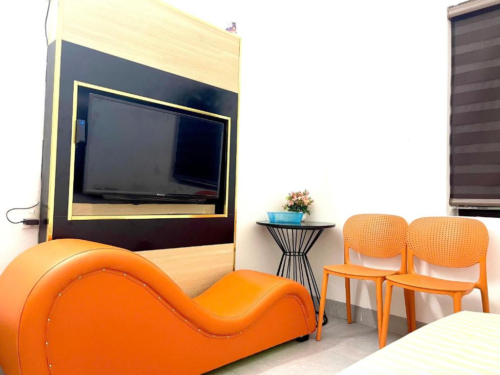 a living room with an orange couch and two chairs at Nhà Nghỉ Hưng Hà in Kon Rung (1)