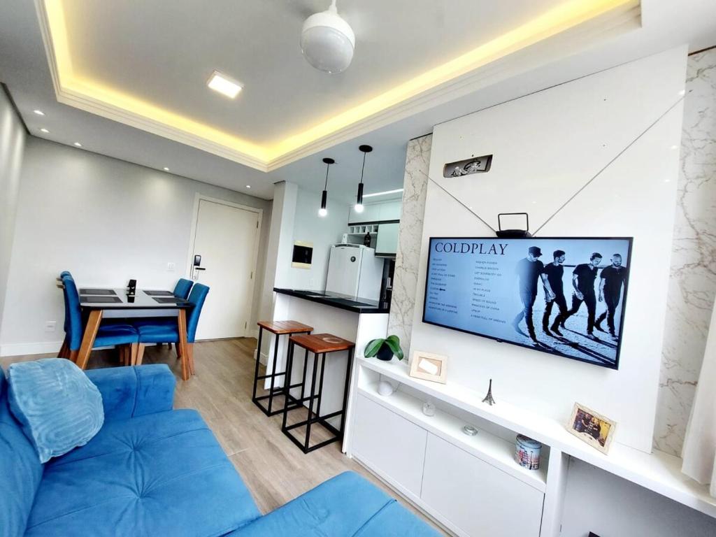 - un salon avec un canapé bleu et une télévision murale dans l'établissement Xingu Reserva Ipanema, à Porto Alegre