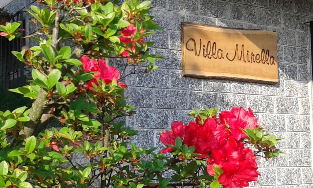ein Schild an der Seite einer Ziegelmauer mit Blumen in der Unterkunft B&B Villa Mirella in Casnate con Bernate