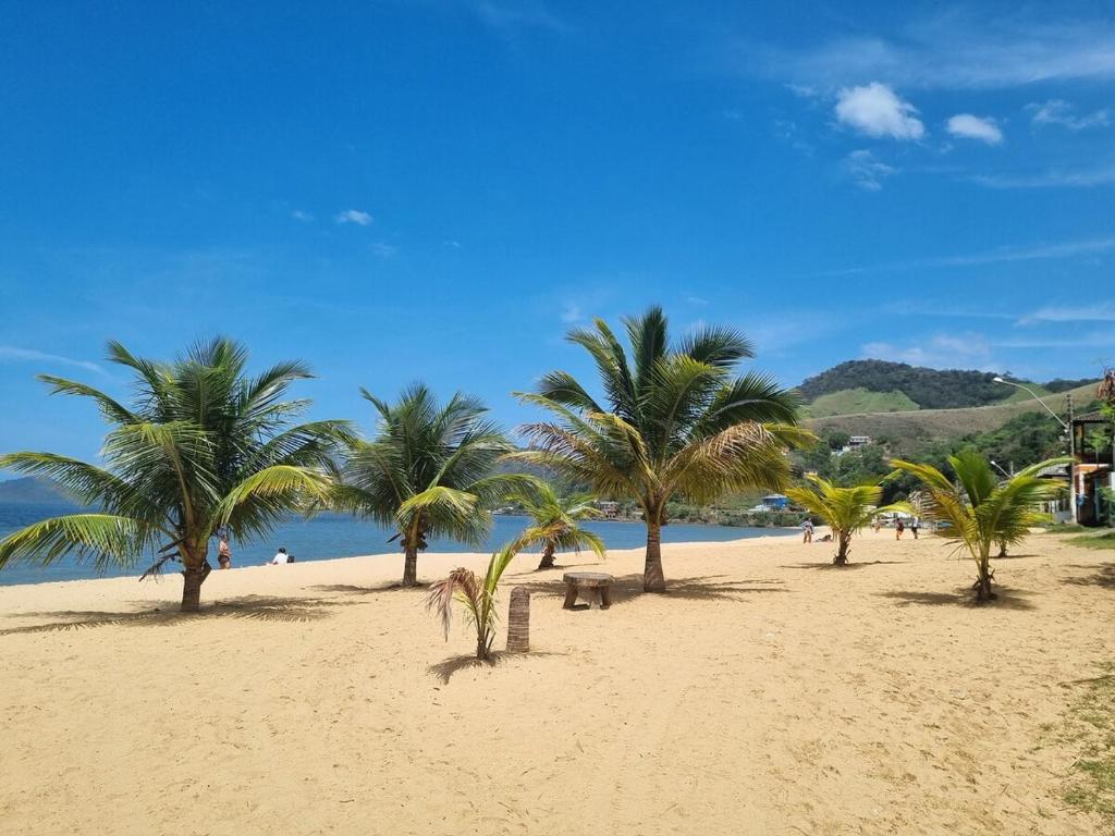 a beach with palm trees and people on it at Casa em Mangaratiba RJ - 40 metros da Praia in Mangaratiba