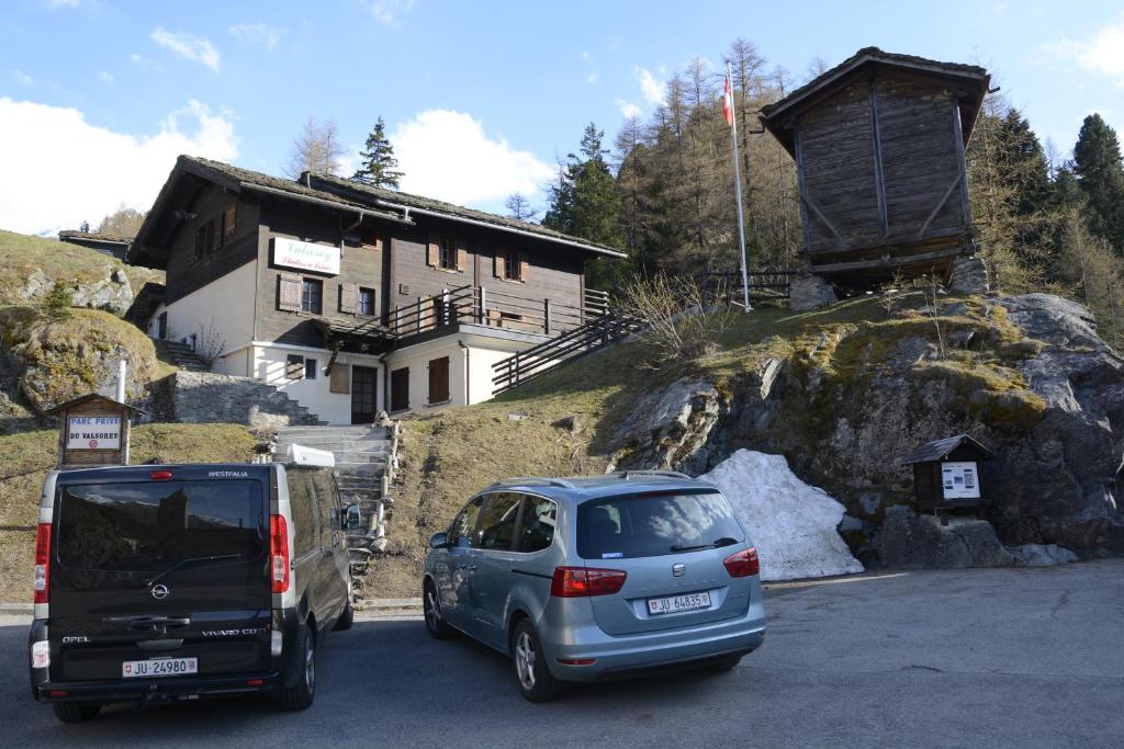 two cars parked in a parking lot in front of a house at Studios du Valsorey in Bourg-Saint-Pierre