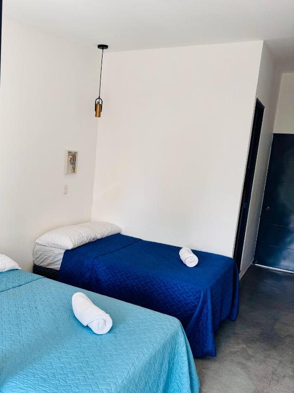 two beds in a room with blue and white sheets at Vibes Wellness House in Tamanique