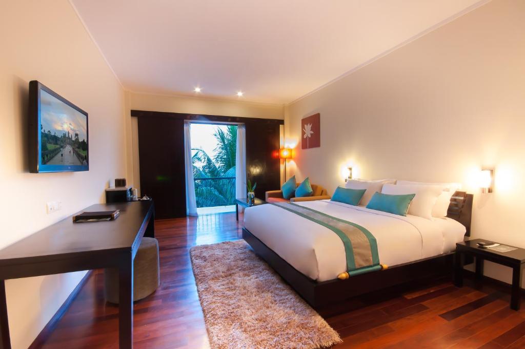 a bedroom with a large bed and a desk at Lotus Blanc Resort in Siem Reap