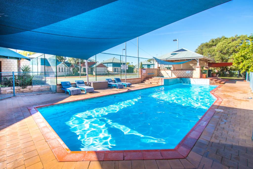 una gran piscina con sombrilla azul en Amalfi Resort en Busselton
