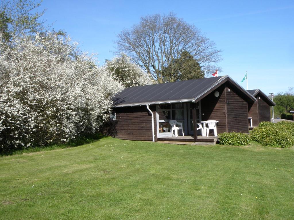 a small house with two white chairs in a yard at Vejle City Camping in Vejle