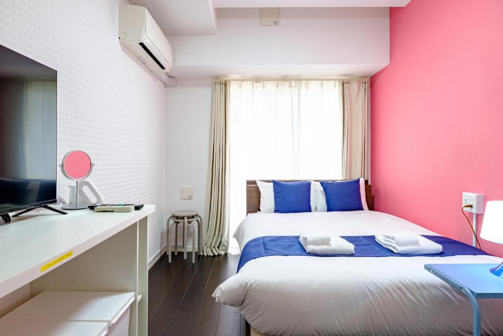Un dormitorio con una pared rosa y una cama en Hatanodai Smart Villa - スマートVilla 旗の台, en Tokio