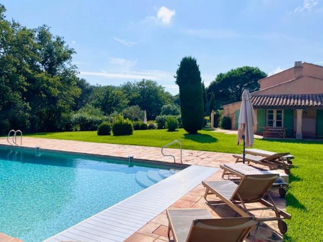 a swimming pool with lounge chairs and an umbrella at Le Petit Domaine in Ramatuelle