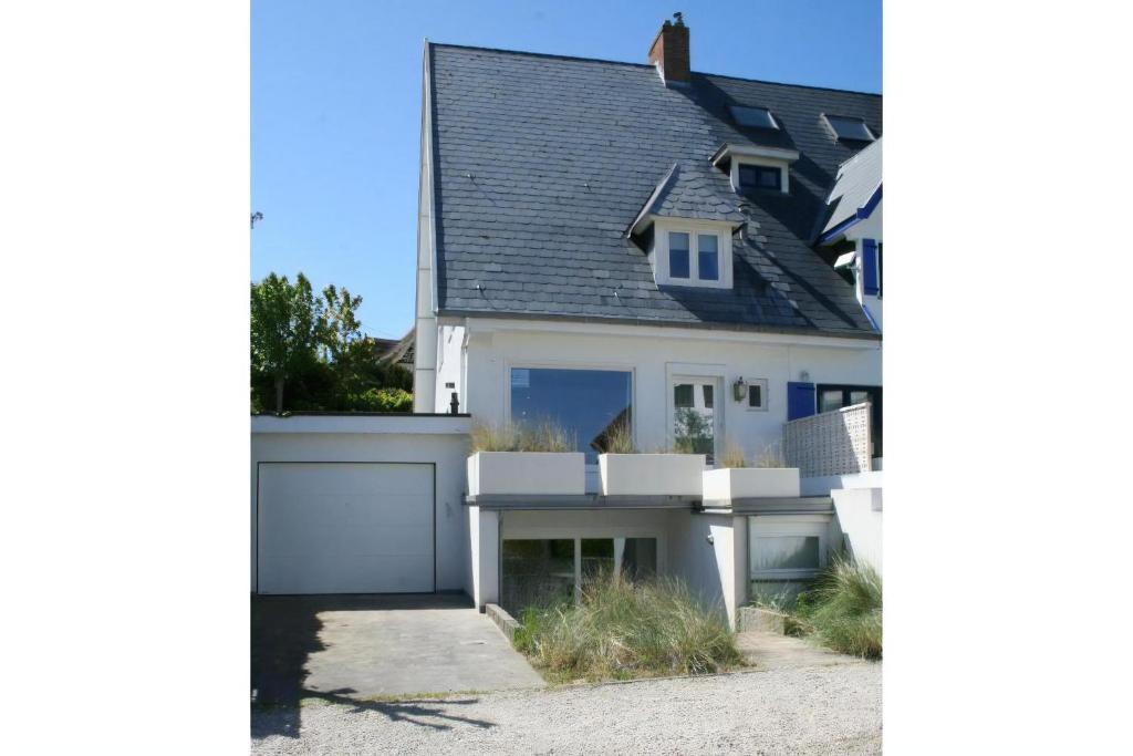 a white house with a black roof at Summer Dream in De Haan