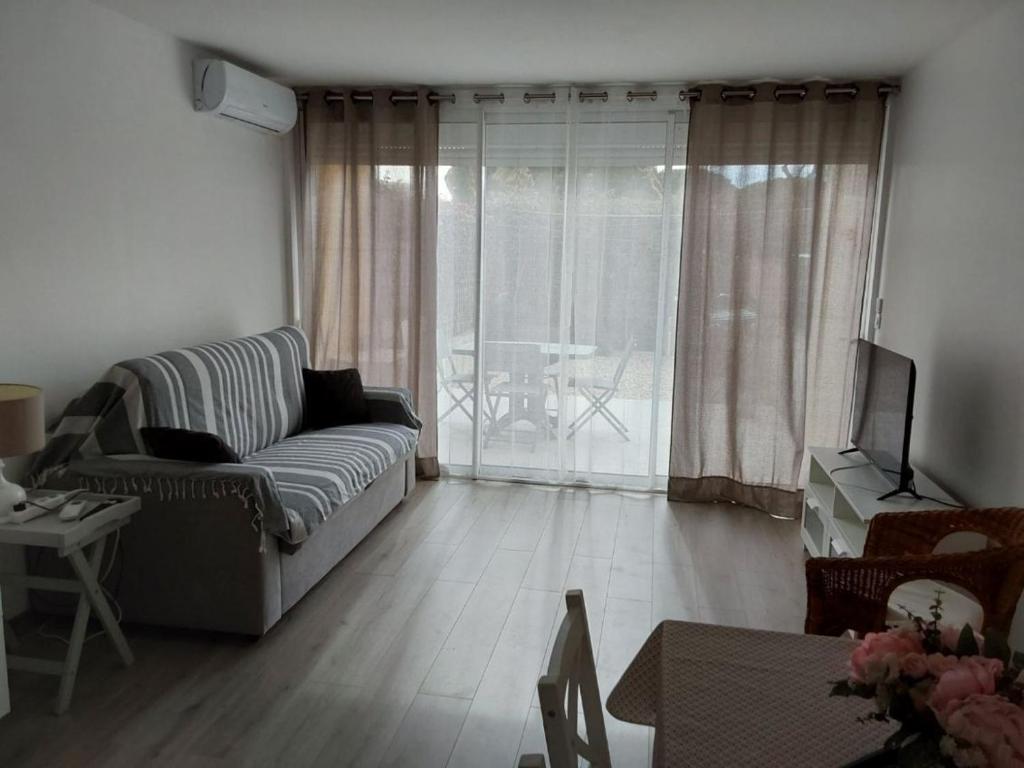 un salon avec un canapé et une télévision dans l'établissement Appartemment Grau du Roi Résidence Camargue village, au Grau-du-Roi