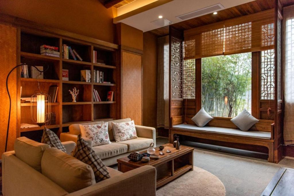 Una sala de estar con un sofá y una ventana. en Ganzhou Banjiangxia Homestay, en Ganzhou