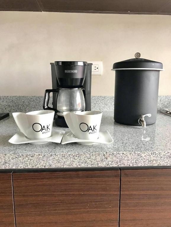two cups and a coffee pot on a kitchen counter at Oak 2B Loft Ejecutivo en zona 10 in La Aurora