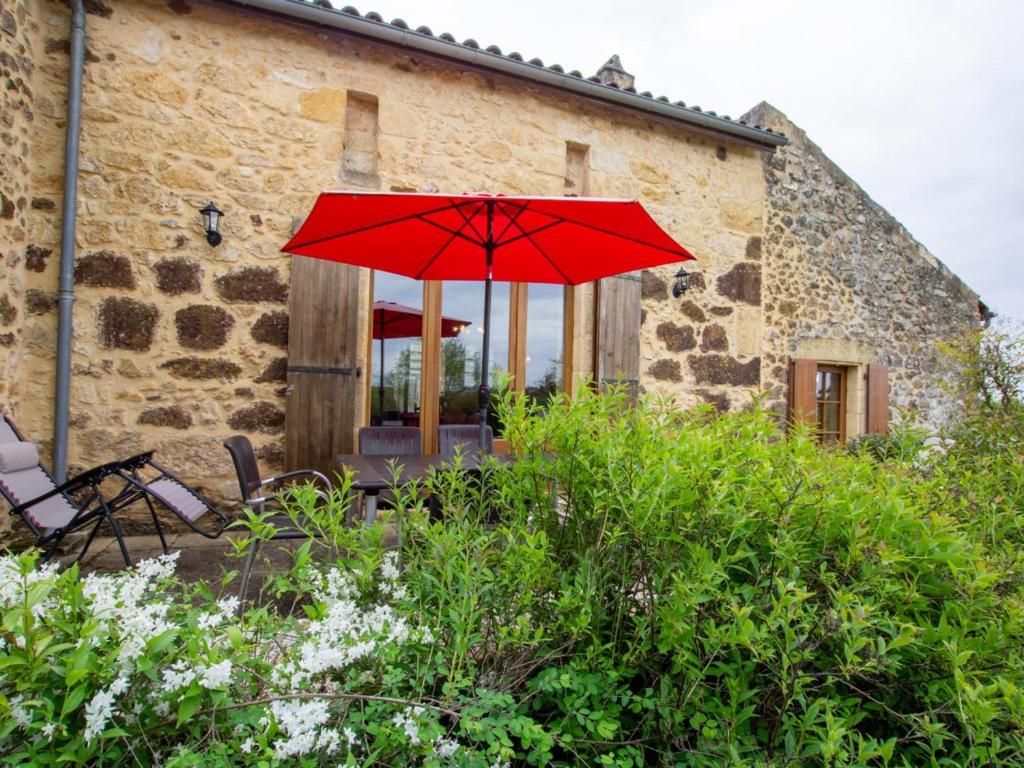 un parapluie rouge devant un bâtiment dans l'établissement Maison 3 chambres avec jardin à Domme - FR-1-616-48, à Domme