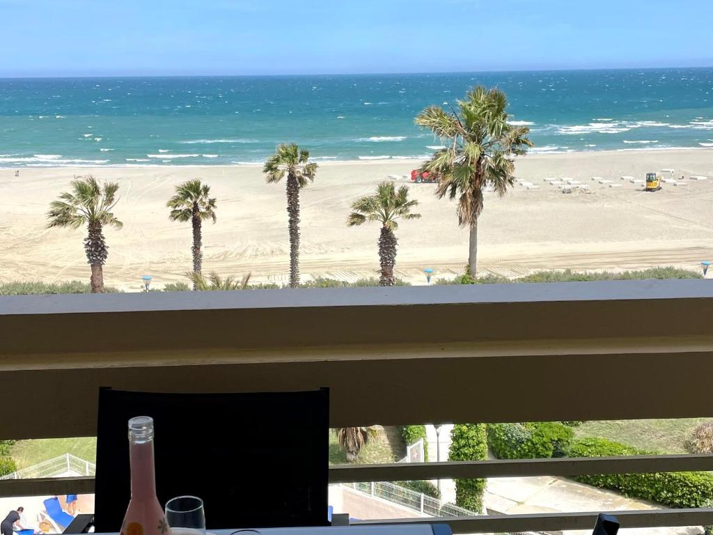 - une fenêtre avec vue sur une plage bordée de palmiers dans l'établissement Superbe appartement avec piscine et parking sécurisé - FR-1-748-33, à Canet