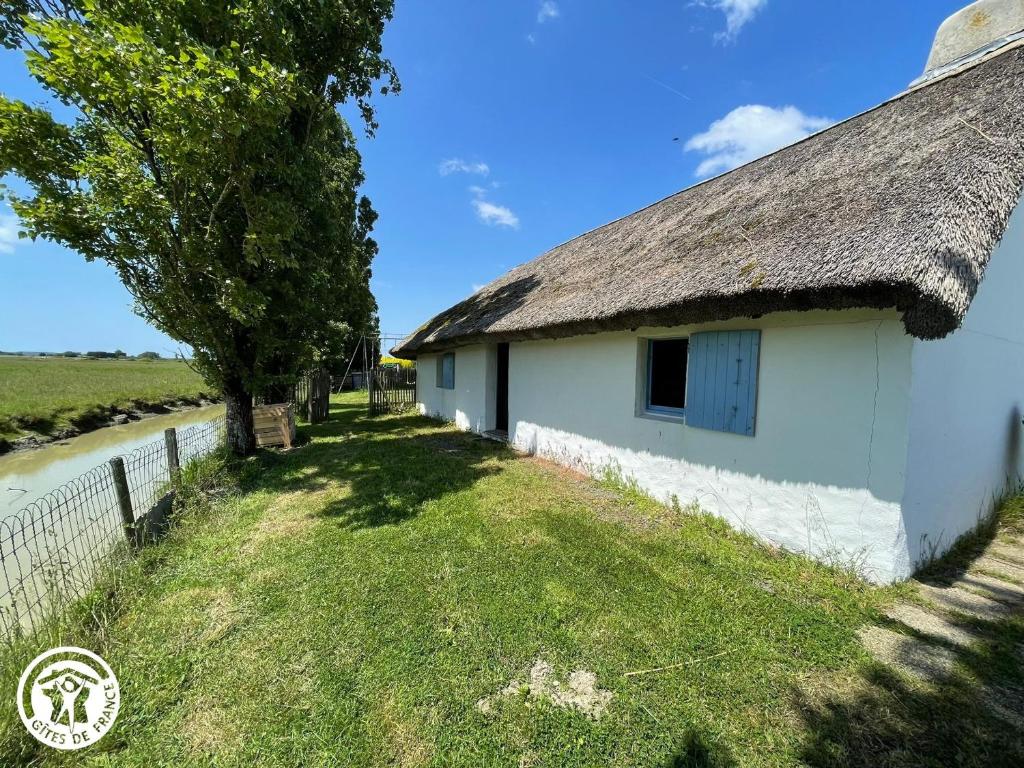 a cottage with a thatched roof and a tree at Charmante chaumière traditionnelle dans le Marais breton - FR-1-426-584 in Beauvoir-sur-Mer