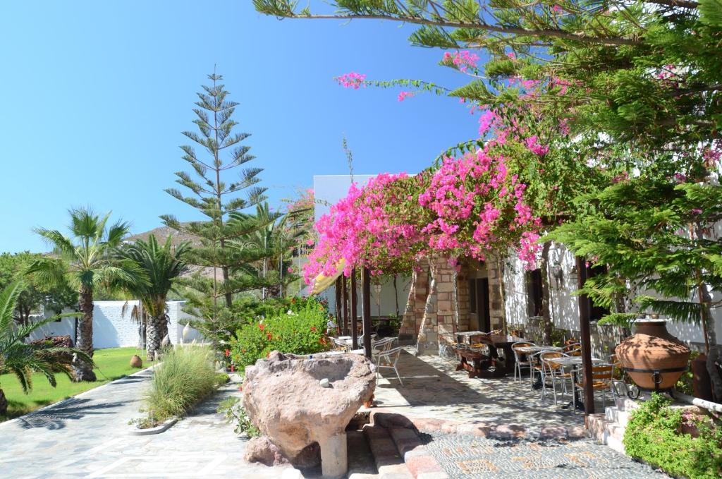 Asteri Hotel في سكالا: حديقة فيها ورد وردي واشجار ومبنى