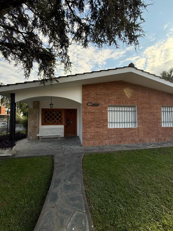 a brick house with a white bench in front of it at Chalet Pino azul in Villa Carlos Paz