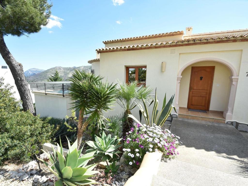 a house with a garden with flowers in front of it at Villa in Monte Pego near Stunning Beaches in Adsubia