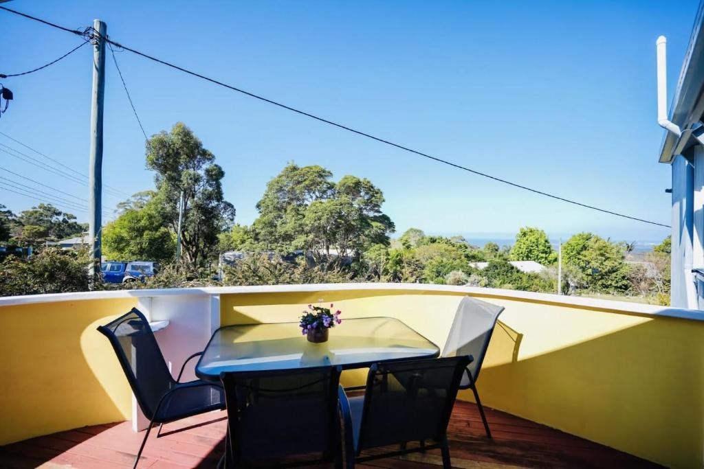 a patio with a table and chairs on a balcony at Serene Mountain Cabin Retreat Tamborine Mountain in Mount Tamborine