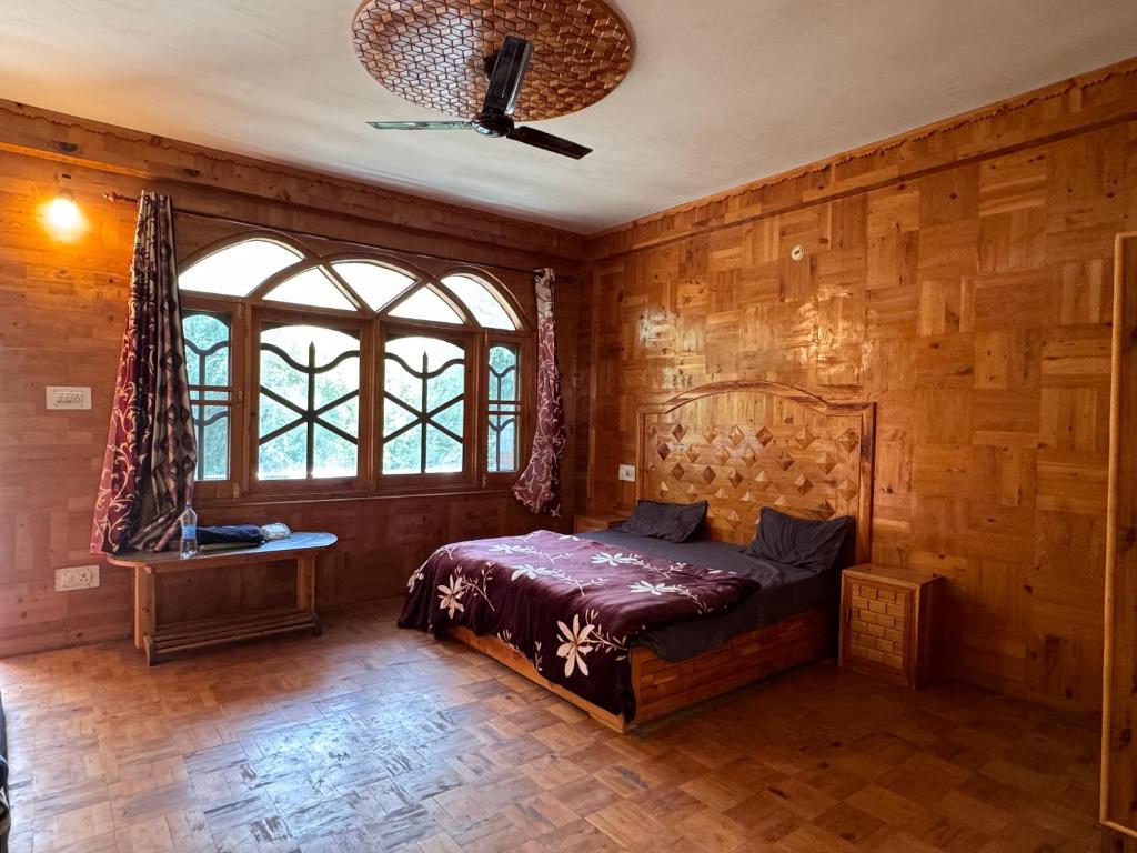 a bedroom with a bed in a room with wooden walls at Parma guest house in Kasol