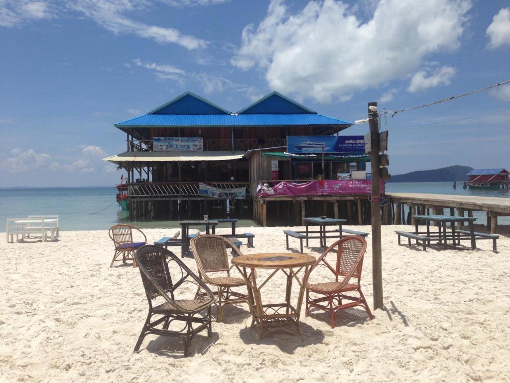 a table and chairs on a beach with a building at Sea House Guest House in Koh Rong Island