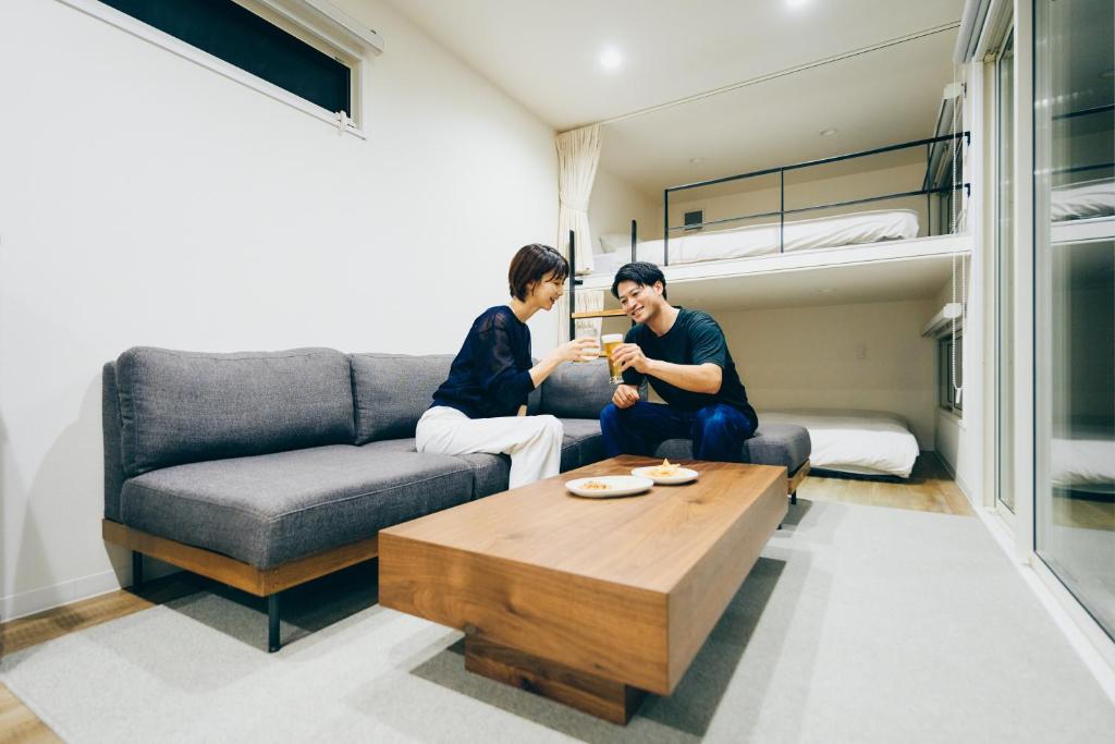 zwei Männer sitzen auf einer Couch in einem Wohnzimmer in der Unterkunft 1NLDK hyuga in Hyuga