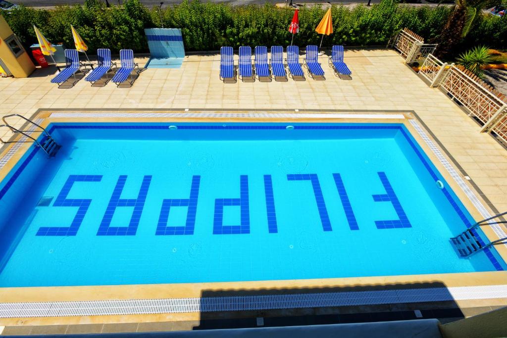 een groot blauw zwembad met stoelen en parasols bij Filippas Rooms in Gouvia in Gouvia
