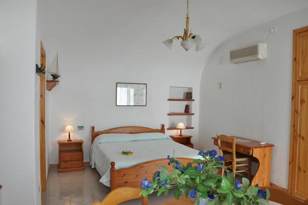 a bedroom with a bed and a desk and flowers at Il Capriccio Guesthouse in Ponza